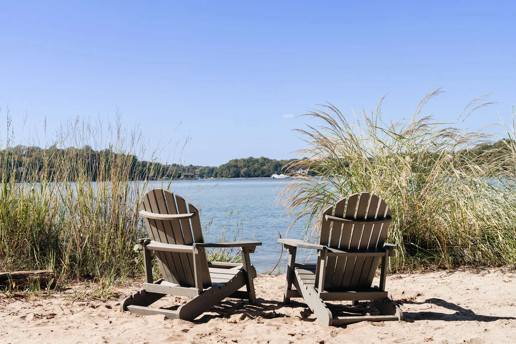 Two Adirondack chairs overlooking the water at Linstead’s community beach