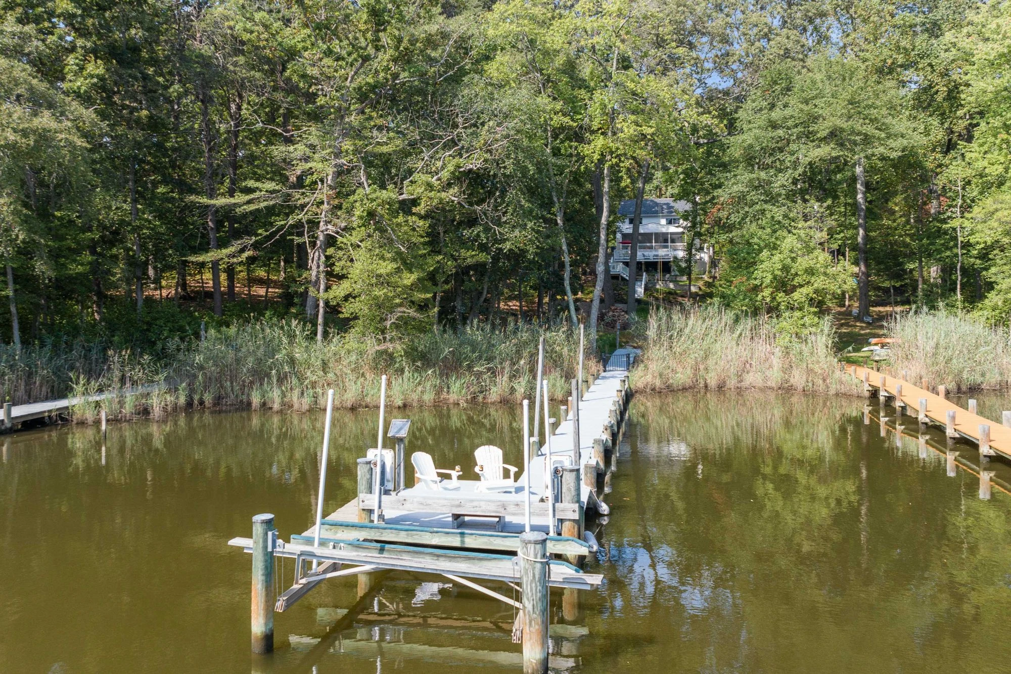 Adirondack chairs on a private pier beside a wooded Severna Park shoreline